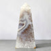Kindred Crystal Collective — Natural Agate Druzy Obelisk, polished cream-toned crystal tower with flowing grey bands and natural crystalline textures.