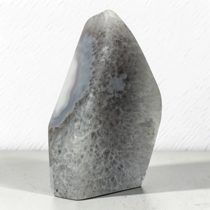 Kindred Crystal Collective — Natural Grey Agate Flame with Druzy Centre, freestanding flame-shaped stone with grey banding and polished and naturally textured surfaces.