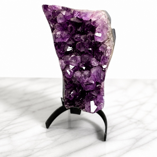 Kindred Crystal Collective — Amethyst Cluster on Stand, large deep violet natural Amethyst druzy cluster on black metal display stand, marble surface, front view