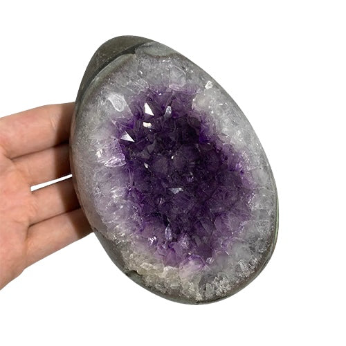 Kindred Crystal Collective — Amethyst Druzy Egg, hand-held polished dark grey Amethyst druzy egg tilted to show full egg silhouette and violet crystal interior, size reference