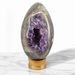 Kindred Crystal Collective — Amethyst Geode Egg, natural amethyst geode in egg form with polished outer shell and deep violet druzy crystal interior, 12.8cm tall
