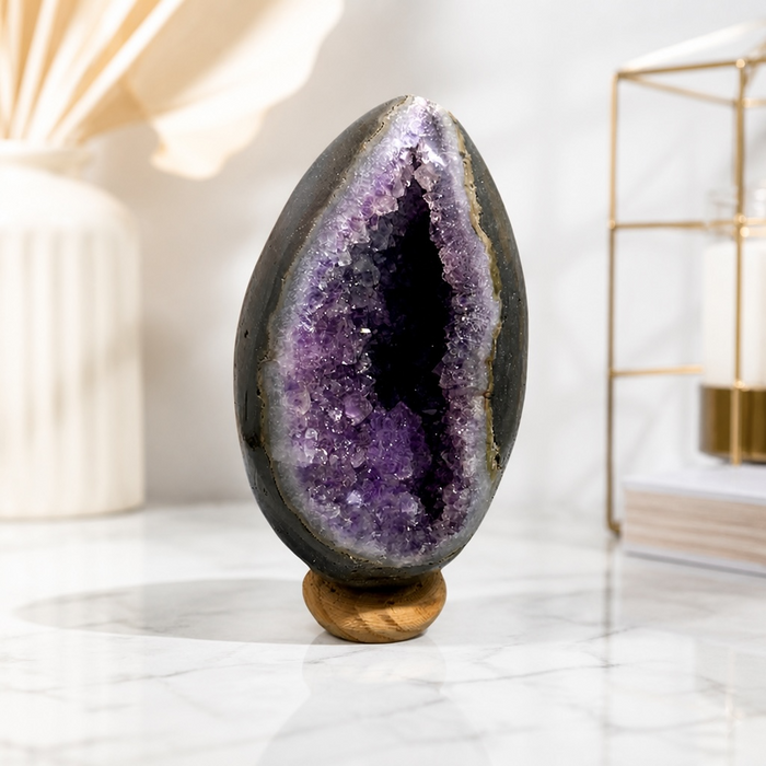 Kindred Crystal Collective — Amethyst Geode Egg, side view of natural amethyst geode egg showing smooth polished exterior and sparkling violet crystal cavity