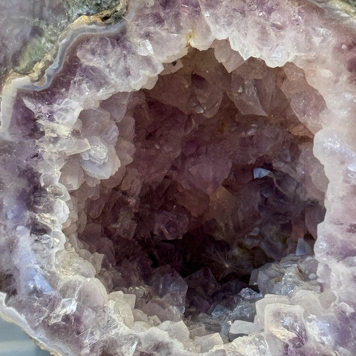 Kindred Crystal Collective — Amethyst Geode Pair, angled view of matched amethyst geode pair highlighting natural volcanic outer shell and sparkling interior