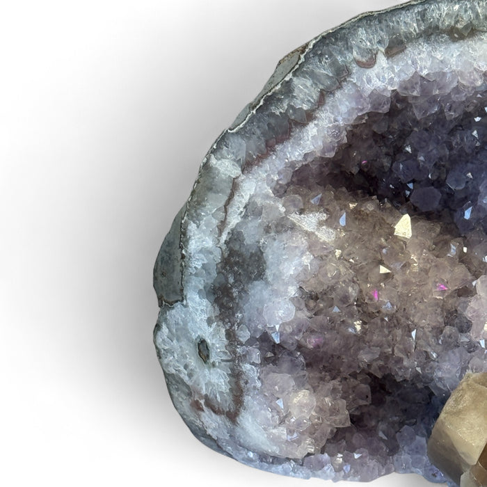 Kindred Crystal Collective — Amethyst Geode With Calcite Inclusion, angled view of natural amethyst geode highlighting calcite inclusion detail and natural matrix base