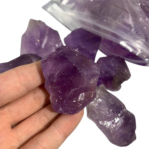 Kindred Crystal Collective — Amethyst Rough 1KG AA+ Grade, rich violet raw amethyst chunks spilling from a clear bag on white background.