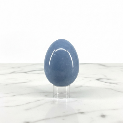 A polished blue stone egg displayed upright on a clear acrylic stand against a white marble surface and white background.