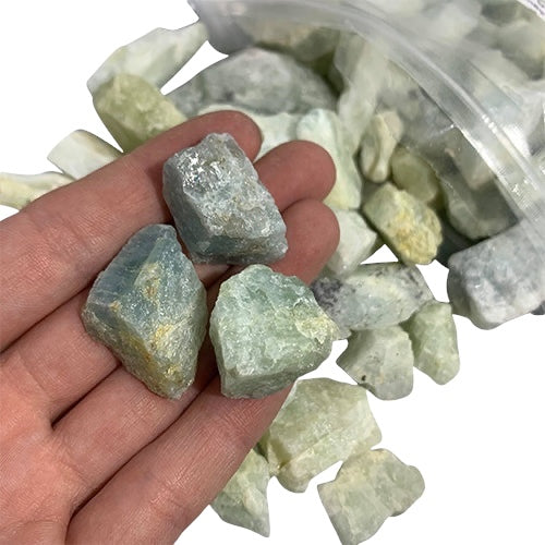 Kindred Crystal Collective — Aquamarine Rough 1KG, soft blue raw aquamarine chunks spilling from a clear bag on white background.