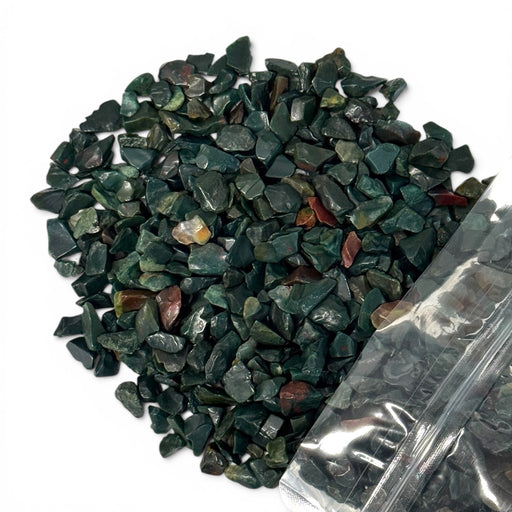 Kindred Crystal Collective — Bloodstone Chips 500g, tumbled deep green bloodstone chips with red and orange jasper inclusions poured from clear bag on white background