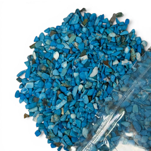 Kindred Crystal Collective — Blue Howlite Chips 500g, vivid turquoise-blue colour-enhanced howlite chips with white matrix, poured from clear bag on white background