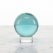 Blue Obsidian Sphere — polished teal volcanic glass sphere on display stand