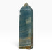 Kindred Crystal Collective — Blue Onyx Obelisk, polished blue-teal stone tower with pale flowing bands, earthy accents and a pointed tip.