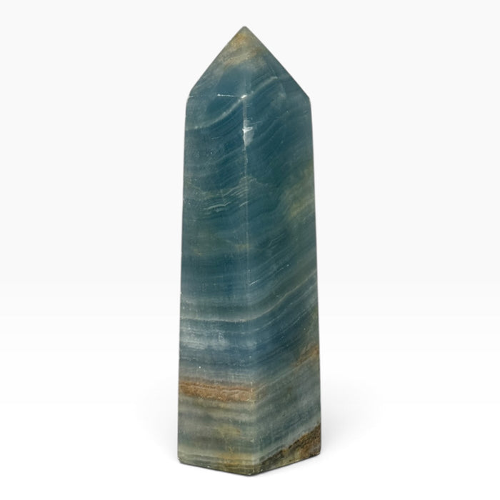 Kindred Crystal Collective — Blue Onyx Obelisk, polished blue-teal stone tower with pale flowing bands, earthy accents and a pointed tip.