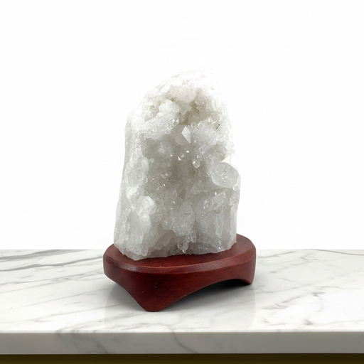 Kindred Crystal Collective - A white crystal geode cluster on a polished reddish-brown wooden display stand, set against a clean white background.