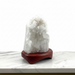 Kindred Crystal Collective - A white crystal geode cluster on a polished reddish-brown wooden display stand, set against a clean white background.