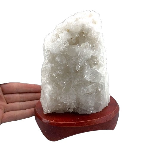 Kindred Crystal Collective — Clear Quartz Cluster Lamp, dense dome-shaped clear quartz cluster on timber lamp base, size reference with hand