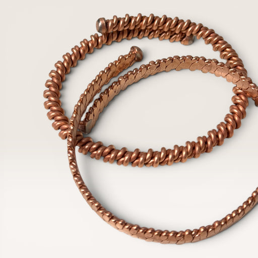 Kindred Crystal Collective — Cubit Tensor Bracelets, two handcrafted pure copper open-cuff bracelets overlapping on white background showing Cubit Tensor style (twisted wire with ball-end tips) and Hammered style (flat woven copper scale band)