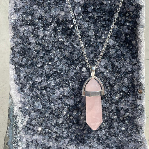 Necklace with a pink crystal pendant on a dark stone surface