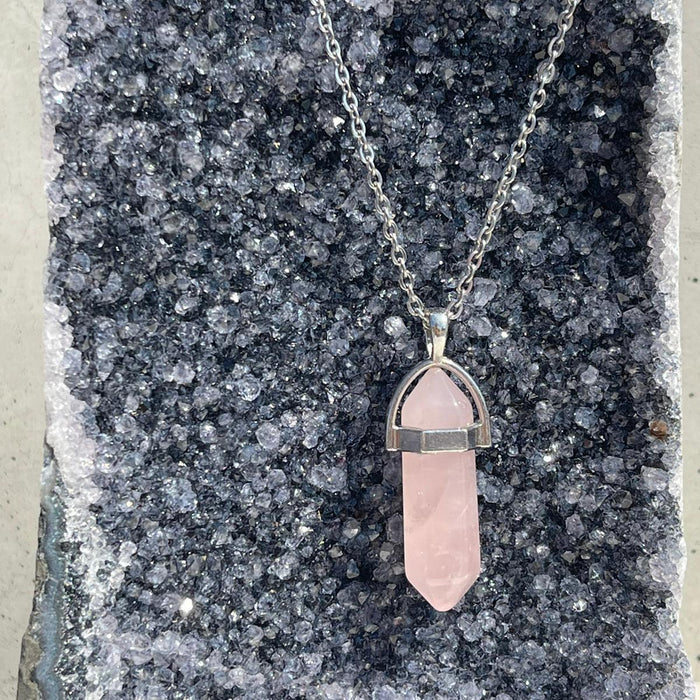 Necklace with a pink crystal pendant on a dark stone surface