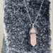 Necklace with a pink crystal pendant on a dark stone surface