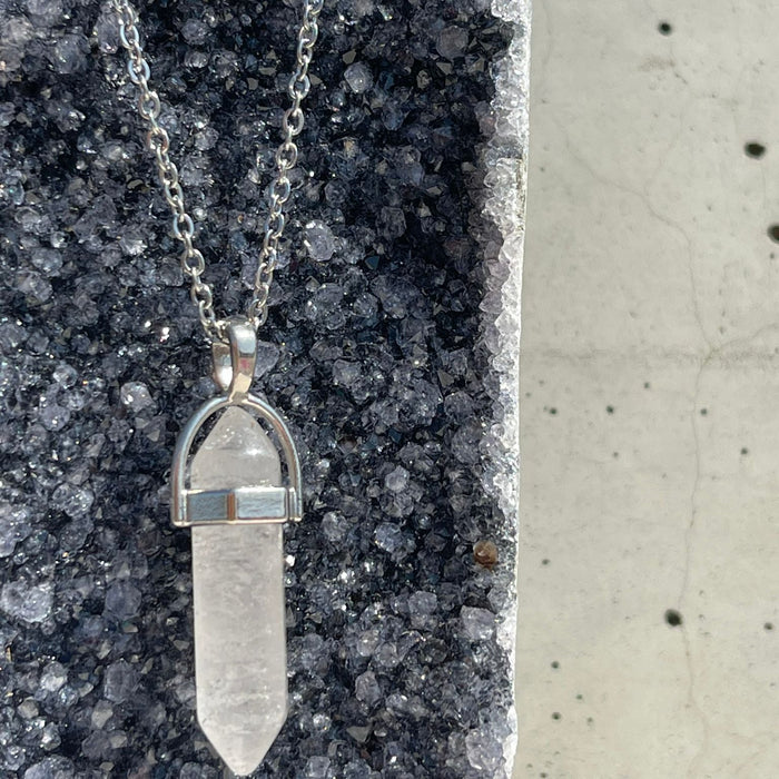 Crystal pendant necklace on a dark stone surface