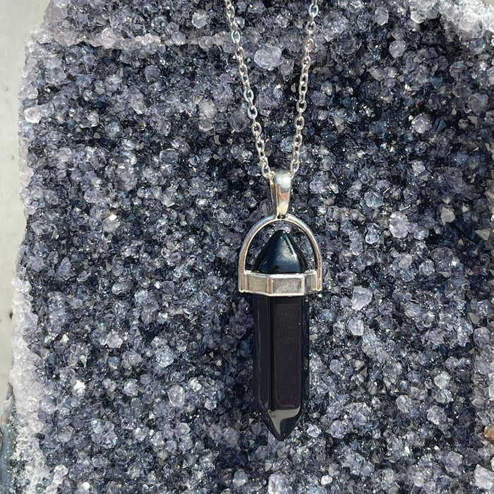 Necklace with a black crystal pendant on a gray stone surface
