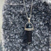 Necklace with a black crystal pendant on a gray stone surface