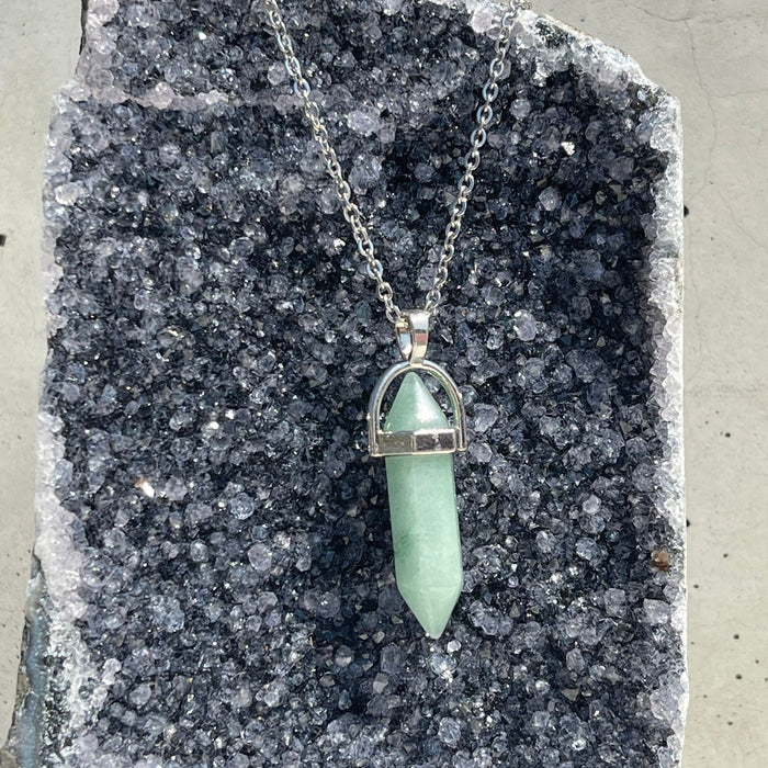 Necklace with a green pendant on a gray stone surface