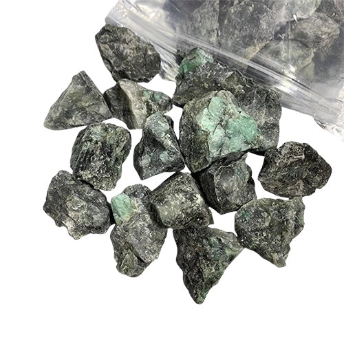 Kindred Crystal Collective — Emerald Rough 1KG, rich green raw emerald chunks spilling from a clear bag on white background.