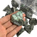 Kindred Crystal Collective — Emerald Rough 1KG, rich green raw emerald chunks spilling from a clear bag on white background.