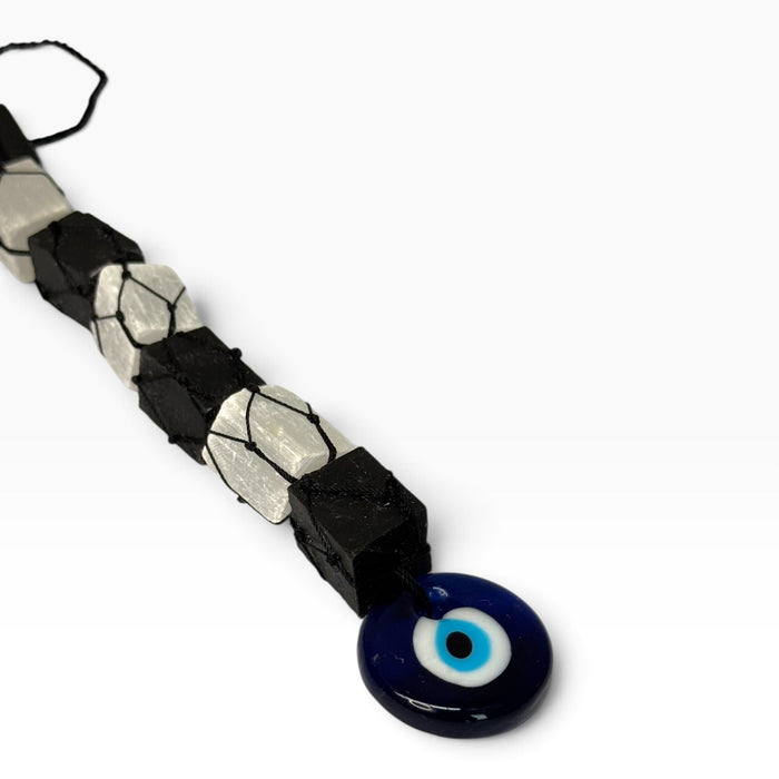 Kindred Crystal Collective — Evil Eye Tourmaline Selenite Macrame Hanger, alternating black tourmaline and white selenite held in black cord with a blue evil-eye charm.