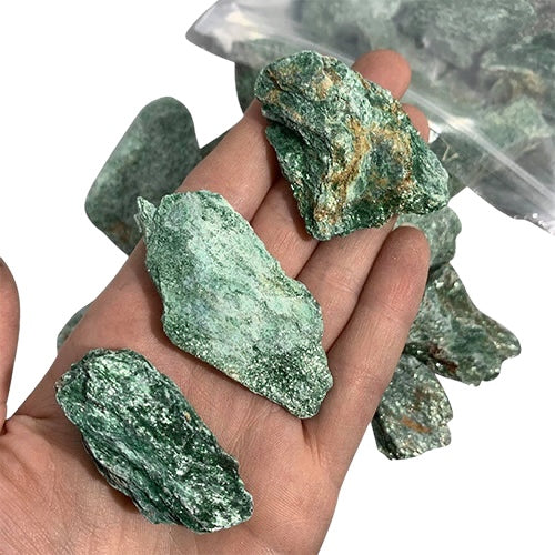Kindred Crystal Collective — Fuchsite Rough 1KG, sparkling emerald-green raw fuchsite chunks spilling from a clear bag on white background.