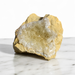 Kindred Crystal Collective — Golden Calcite Cluster, natural raw Golden Calcite specimen with warm amber-yellow matrix and pale cream-white druzy crystal face, displayed on white marble surface