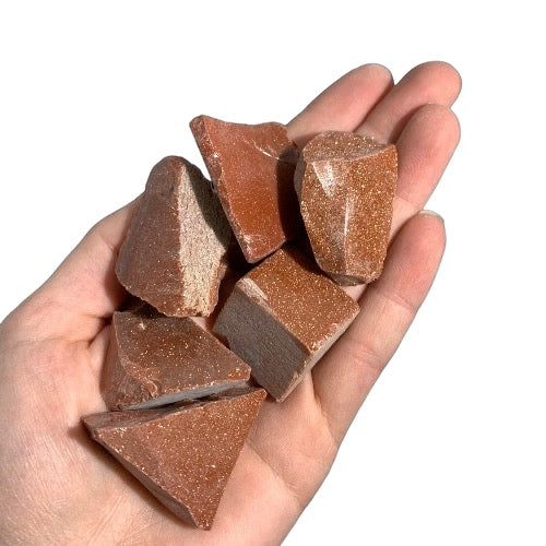 Kindred Crystal Collective — Goldstone Rough 1KG, glittering orange-gold raw goldstone chunks spilling from a clear bag on white background.