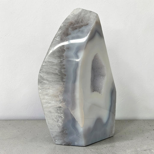 Kindred Crystal Collective — Natural Grey Agate Flame with Druzy Centre, freestanding flame-shaped stone with grey banding and polished and naturally textured surfaces.
