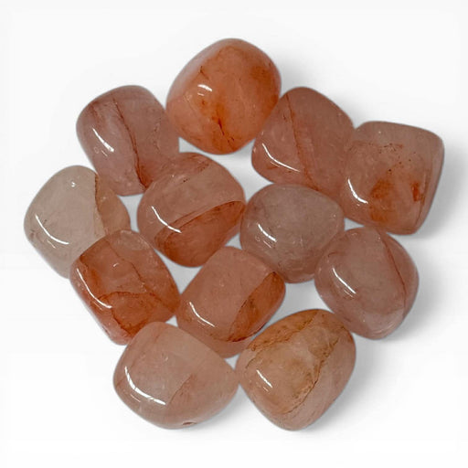 Kindred Crystal Collective — Hematoid Quartz Tumbled Stones, pile of polished Fire Quartz tumbles showing warm peach to rust-orange colouring with natural Hematite streaking and semi-translucent Quartz body, white background
