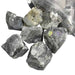 Kindred Crystal Collective — Labradorite Rough 1KG, dark grey raw labradorite chunks spilling from a clear bag on white background.
