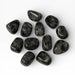 Kindred Crystal Collective — Larvikite Tumbled Stones, pile of polished dark charcoal-grey Larvikite tumbles showing coarse-grained feldspar crystal mosaic surface with high-gloss finish, white background