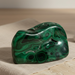 Green malachite stone on a beige cloth with a wooden surface