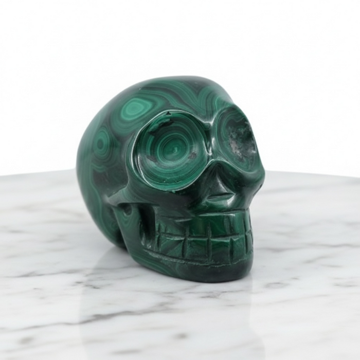 Malachite skull 180g showing striking green concentric banding, a powerful stone of transformation for third eye and heart chakra activation
