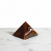 Kindred Crystal Collective - A polished pyramid agate crystal pyramid with natural banding in dark brown, amber, and white, displayed on a white marble surface against a white background.