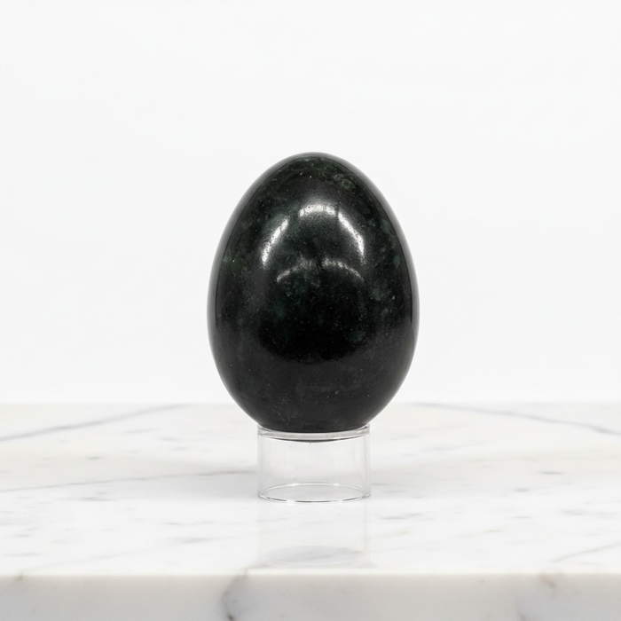 Kindred Crystal Collective - Nephrite Jade egg on a clear stand, showing deep dark green colouring with a smooth high-gloss finish.