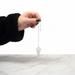 Kindred Crystal Collective — Opalite Pendulum, faceted iridescent opalite pendulum held on silver chain, white background