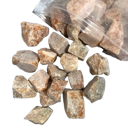 Kindred Crystal Collective — Orchid Calcite Rough 1KG, soft peach and lavender raw calcite chunks spilling from a clear bag on white background.

