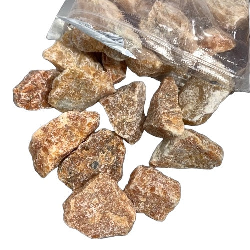 Kindred Crystal Collective — Orchid Calcite Rough 1KG, soft peach and lavender raw calcite chunks spilling from a clear bag on white background.