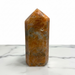 Kindred Crystal Collective — Orchid Calcite Generator, polished warm amber-orange orchid calcite generator point, angled view showing mottled surface detail