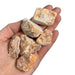 Kindred Crystal Collective — Orchid Calcite Rough 1KG, soft peach and lavender raw calcite chunks spilling from a clear bag on white background.