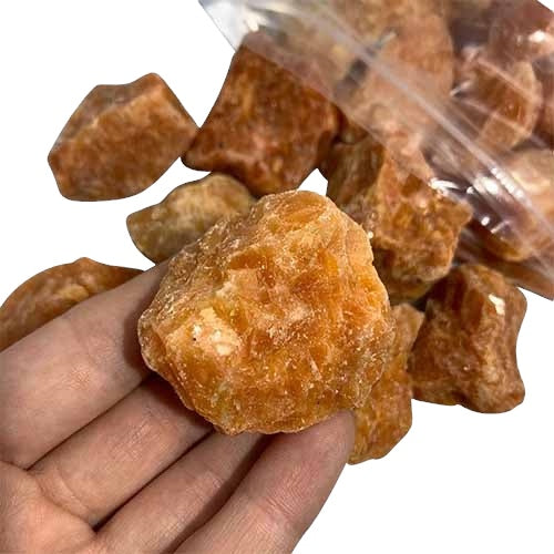 Kindred Crystal Collective — Orchid Calcite Rough 1KG AA+ Grade, soft peach and lavender raw calcite chunks spilling from a clear bag on white background.