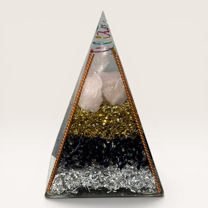 Kindred Crystal Collective — Orgonite Pyramid, handcrafted clear resin pyramid with layered clear quartz, black obsidian, brass shavings, copper frame and multicoloured spiral apex, white background