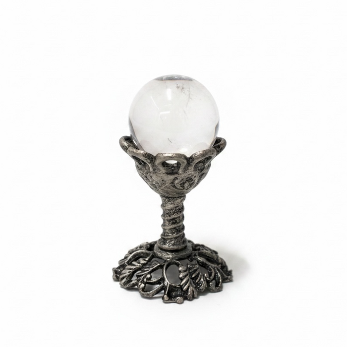Decorative object with a white sphere on an ornate metal stand against a white background