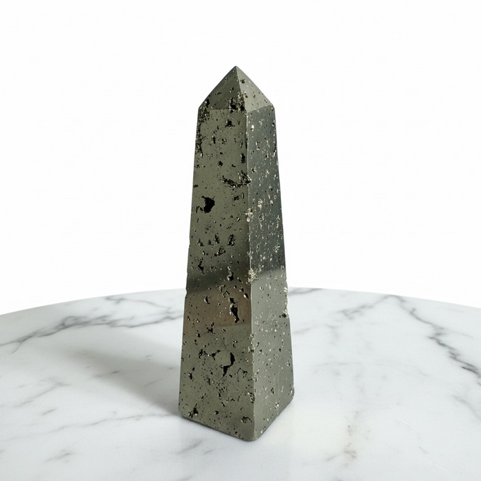 Kindred Crystal Collective — Pyrite Obelisk, polished natural pyrite obelisk with metallic golden-grey cubic crystal surface, white background